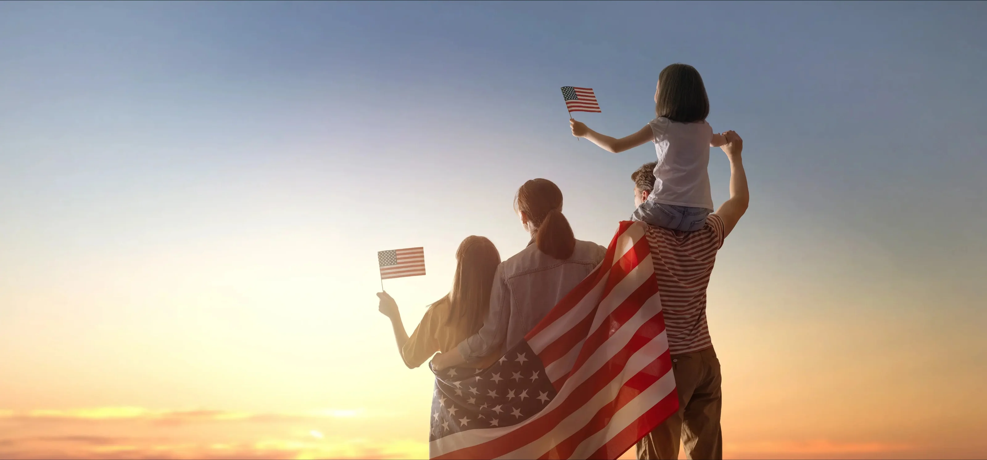 An American family at sunset holding American flags